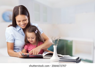 Youngmother helping teen daughter remote studying at home explaining doing homework together.