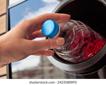 A young's girl hand putting an empty plastic water bottle to recycle in a recycling machine, close up - Powered by Shutterstock