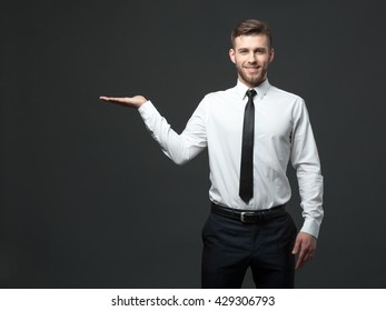 Your Logo Or Product Goes Here! Studio Shot Of Handsome Young Businessman Holding His Arm Up Presenting Copyspace.