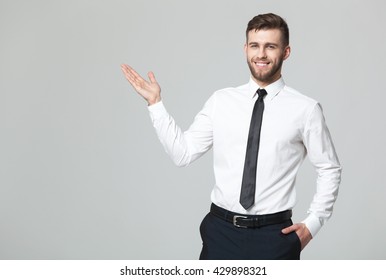 Your Logo Or Product Goes Here! Studio Shot Of Handsome Young Businessman Holding His Arm Up Presenting Copyspace.