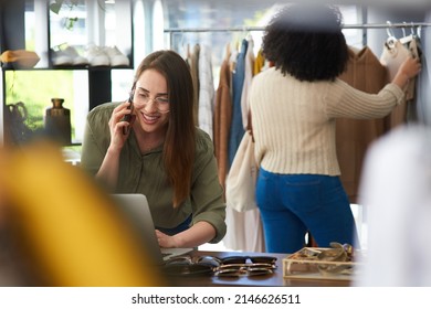 Your order is packed and on its merry way. Shot of a woman talking on her cellphone while working in a clothing store.