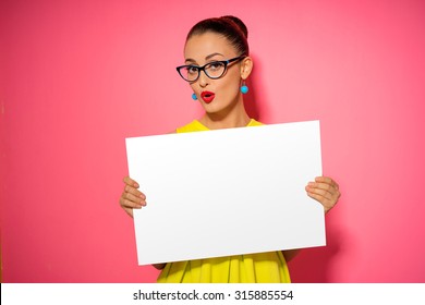 Your Text Here. Pretty Young Excited Woman Holding Empty Blank Board. Colorful Studio Portrait With Pink Background.