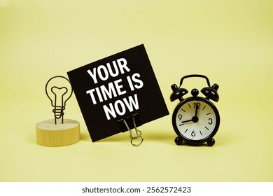 Your Time Is Now text message on sticky note with alarm clock on yellow background