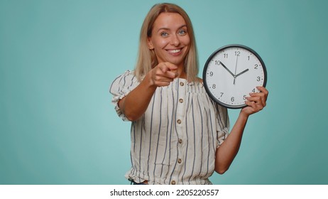 It Is Your Time. Portrait Of Blonde Young Woman In Shirt Showing Time On Clock Watch, Ok, Thumb Up, Approve, Pointing Finger At Camera. Adult Girl Indoors Studio Shot Isolated Alone On Blue Background