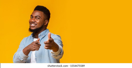 It's your turn. Handsome black guy pointing fingers at camera and smiling over yellow background