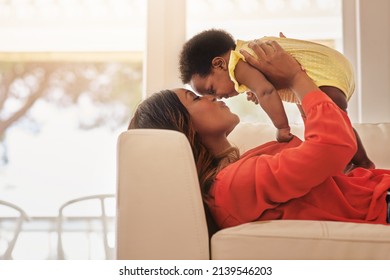 Youre My Definition Of Perfect. Shot Of A Mother Holding Up Her Baby While Lying On Her Sofa At Home.