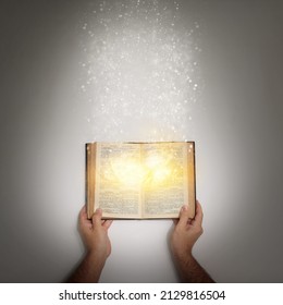 Youre Never Too Old For A Fairytale. Shot Of A Hand Holding An Open Storybook With Light Emanating From It.