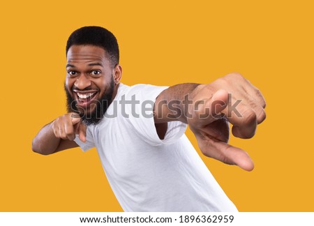 You're next. Funny african man pointing fingers at camera posing in studio on yellow background. I choose you concept, advertisement banner with cheerful black guy