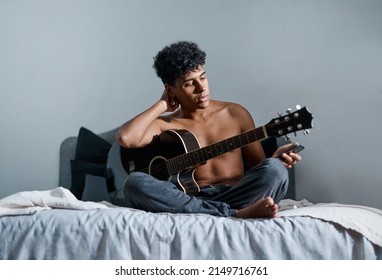 Youre Not A Musician Until Youve Written A Breakup Song. Shot Of A Young Man Using A Smartphone While Playing The Guitar At Home.