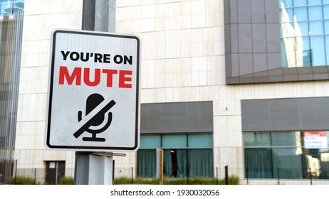 You're on mute sign in a downtown city setting