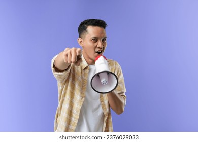 Youre our winner of the day. Studio shot of a asian man using a megaphone against a purple background.