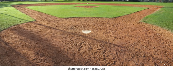 A youth baseball field viewed from behind home plate in morning light