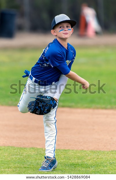 Youth baseball player in blue\
uniform following through on throw made in the infield during a\
game.