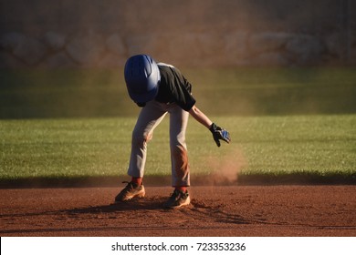 Youth Baseball Player Dusting Off Infield Dirt On Second Base