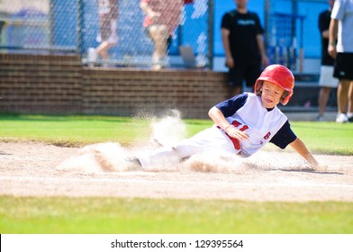 Youth baseball player sliding in at home.