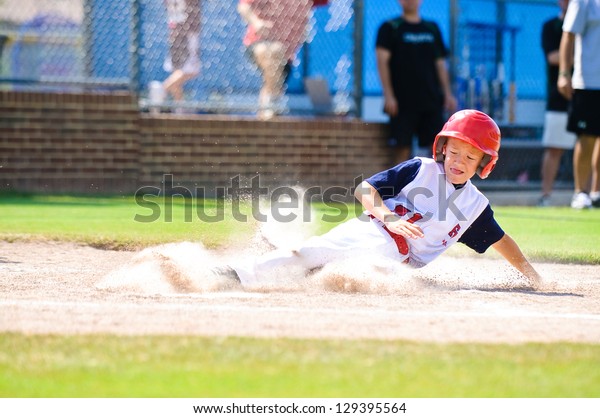 Youth baseball player\
sliding in at home.