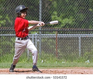 A Youth Baseball Player Takes A Nice Swing At The Ball At Home Plate.