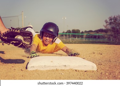 Youth Baseball playing sliding back to base. Focus on glove and ball