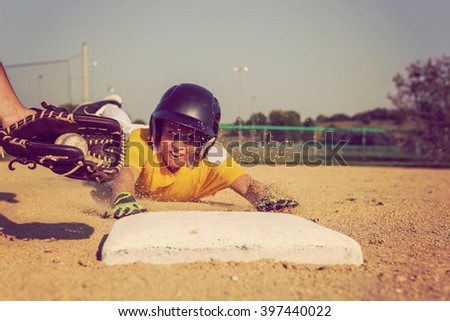 Youth Baseball playing sliding back to base. Focus on glove and ball