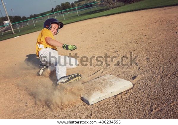 Youth Baseball playing sliding back to base. focus\
on base and foot