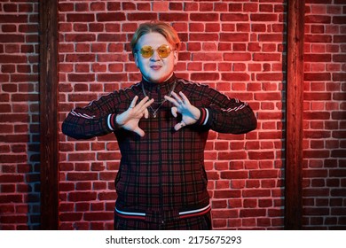 Youth Culture. A Modern Guy With Red Hair And Short Beard Wearing A Casual Sports Suit Is Dancing A Street Dance On A Dark Grunge Background. Hip-hop Culture.