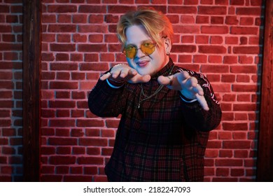 Youth Culture. A Modern Guy With Red Hair And Short Beard Wearing A Casual Sports Suit Is Dancing A Street Dance On A Dark Grunge Background. Hip-hop Culture.