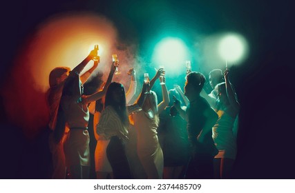 Youth culture, night lifestyle. Vising concert. Group of young, active people at the night club, party dancing in neon lights. Concept of party, fun, holiday, relaxation, meeting Copy space for ad