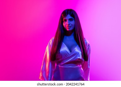 Youth Culture. Portrait Of Young Beautiful Girl On Gradient Pink Background In Neon Lights. Female Model Tenderly Looking At Camera. Trendy Fashion. Concept Of Human Emotions, Facial Expression, Ad