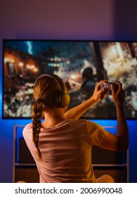 Youth Culture, Video Games. A Woman Is Sitting In A Room With A Joystick In Her Hand. In Front Of Her Is A Large Personal Computer Monitor. There Is Neon Light In The Room. Rest Time, Hobby.