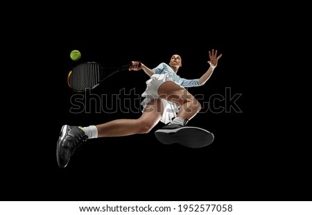Youth. Female professional tennis player in action, motion isolated on black background, look from the bottom. Concept of sport, movement, energy and dynamic, healthy lifestyle. Training, practicing.