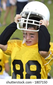 Youth Football Player Putting On Helmet At Game.