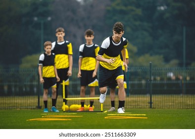 Youth Football Player Running on Training Drill. Teenagers in Soccer Training Sportswear Exercising Outdoor. Sports Educational Equipment. Junior Football Club Practice Session - Powered by Shutterstock