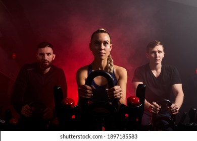 Youth In The Gym, Exercising Their Legs Doing Cardio Training, Having Spinning Class At Gym In Dark Neon Lighted Smoky Space