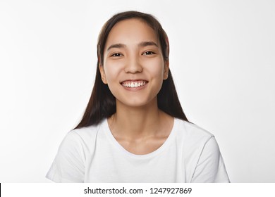 Youth, Joy And Happiness Concept. Adorable Charming Young Korean Female Wearing White T-shirt, Laughing At Joke While Watching Stand Up Comedy At Home, Posing Isolated At Blank Studio Wall