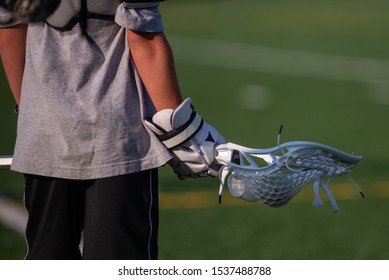 A Youth Lacrosse Player Holding A Men's Lacrosse Stick On A Lacrosse Field. 