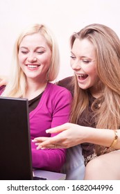 Youth Lifestyle Concepts. Two Happy Expressive Positive Caucaisan Girlfriends Having Fun. Working With Laptop Computer Indoors. Vertical Image Orientation