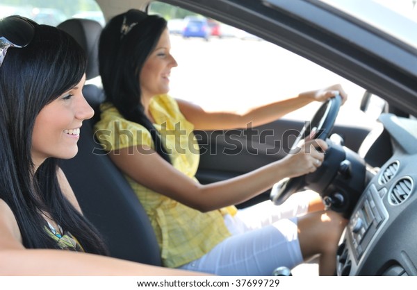 Youth lifestyle - two smiling friends (women) driving\
in car