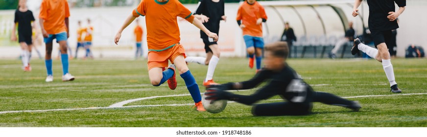 Youth Players Kicking Soccer Match On Grass Stadium. Kids Kicking Football Ball. Boys Play Soccer On Grass Field. Soccer Bench In The Background. Youth Football Tournament