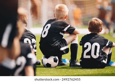 Youth soccer football team. The soccer team is practicing penalty kicks. Group photo. Soccer players sitting together at training. Teammates at youth soccer league game - Powered by Shutterstock