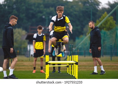 Youth Soccer Team on Training. Young Boys in Football Club Practicing Durability. Teenage Boy Jumping High Over Hurdle Obstacles. Young Men Coaching Sports Team on Practice Field. Youth Soccer School - Powered by Shutterstock