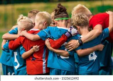 Youth Sports Coach Witch Children On Soccer Field. Kids Huddling Before The Final Tournament Match. Kids Bending Down In Huddle