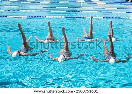 Youth synchronized artistic swimming team in a pool practicing for a competition