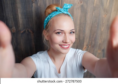 Youth and technology. Young attractive smiling woman taking selfie on camera against wooden wall.