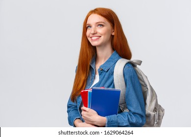 Youth, Teenagers And Education Concept. Determined Good-looking Dreamy And Upbeat Smiling Redhead Female Student With Notebooks And Backpack Looking Forward New Theme In Class