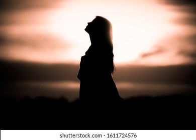 Youth woman soul at golden sun meditation dreaming past times. Silhouette in front of sunset or sunrise in summer nature. Symbol for healing burnout therapy, wellness relaxation or resurrection