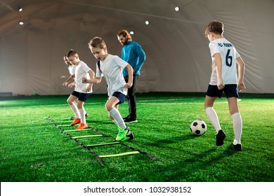 Youthful kids in uniform exercising during football training on green lawn