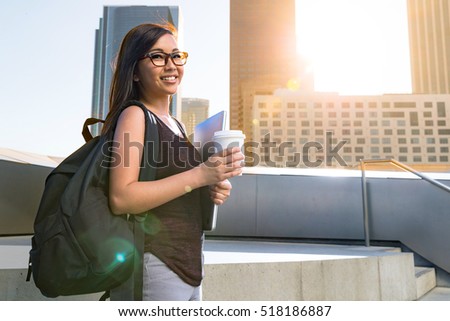 Youthful positive cheerful confident energetic female college student in city downtown buildings 