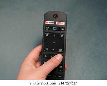 Youtube and Netflix buttons on the remote control. Smart TV remote with function YouTube and Netflix. Woman hand holding television remote control. Prague - April, 2021