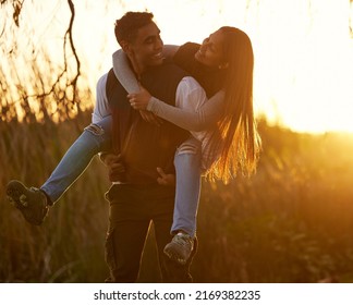 Youve become so strong lately. Shot of a young man giving his girlfriend a piggyback ride. - Powered by Shutterstock