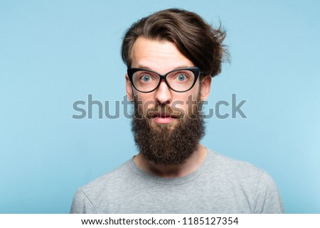 yuck. disgusted revolted bearded hipster guy wearing cat eye glasses. stylish modern fashionist. portrait of a geeky quirky eccentric man on blue background.